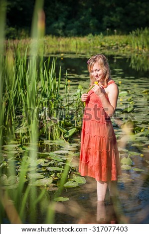 beautiful girl stands in the water. girl holding a flower water lily in his hands