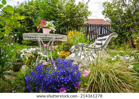 Summer home garden with white bench and a table