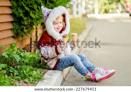 Little girl eating ice cream while sitting on the sidewalk