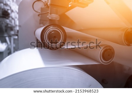 Paper alignment unit on the die-cutting machine for the production of self-adhesive labels in the printing house. Paper feeding on the rollers of the machine. Selective focus ストックフォト © 