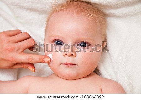 Mother creaming cute infant girl face