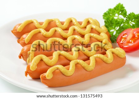 Boiled sausages with mustard on a plate