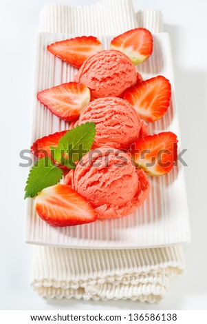 Three scoops of strawberry ice cream with fresh fruits on a tray