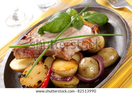 Roasted pork chop and potatoes on a skillet