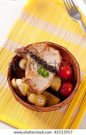 Juicy pork chop and potatoes in a terracotta bowl