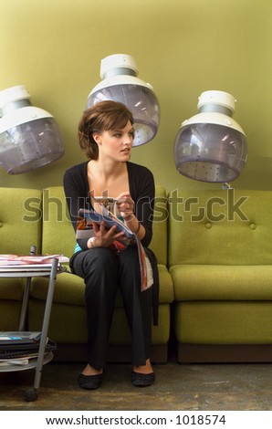 Young woman reads a magazine while waiting in a hairdressing salon