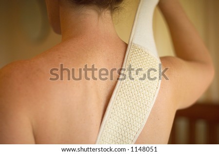 Female using body exfoliating scrub on her back