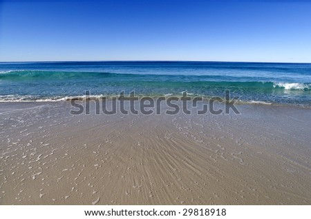 Clear blue water and smooth clean sand on an untouched pristine beach