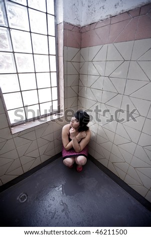 Girl in a Pink Dress alone in a shower room, crouched in the corner