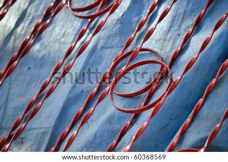 Red Abstract pattern of circles and lines formed by a temporary red metal fence lying on blue plastic sheeting(deliberate very shallow depth of field)