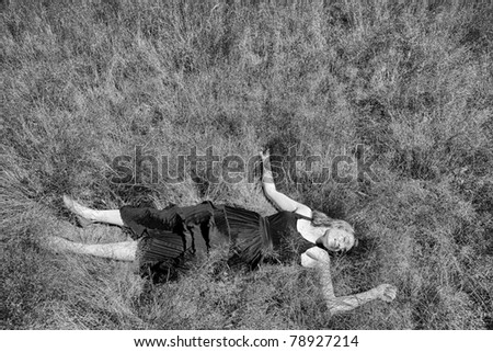 Aerial view of girl in long dress lying on her back in field of long grass
