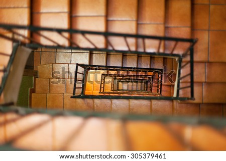 Looking down internal staircase in apartment building, with tiled steps and metal hand rails
