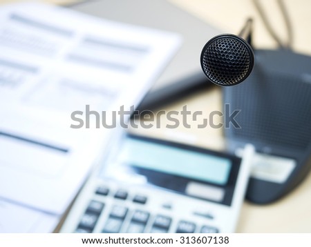 Black microphone in conference room or symposium event with de focused laptop ,document sheet and calculator.