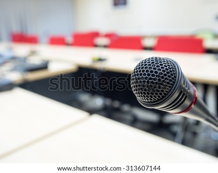 Black microphone in conference room or symposium event with de focused laptop is working in background.