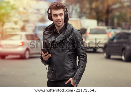 man in headphones on the street. Standing with phone in hand
