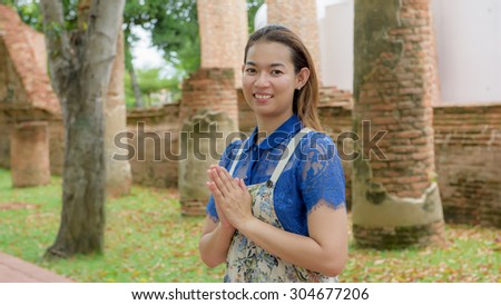 Thai woman standing with hands clasped (Sawasdee - Thai greeting) in Thai temple.