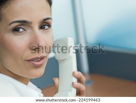 Woman holding phone and talking over shoulder