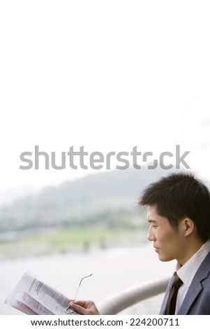 Businessman holding newspaper and glasses