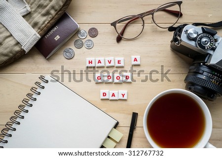 Outfit of traveler and word Have a Good Day spelled using letter tiles on wooden background