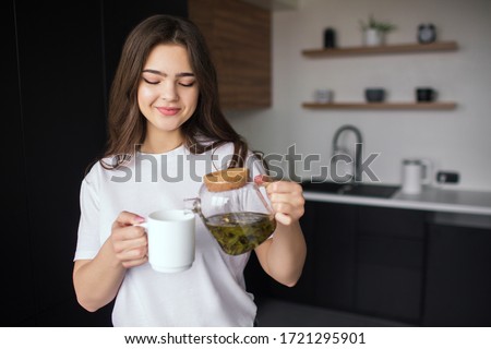 Similar – Image, Stock Photo Woman pouring green tea in mug on wooden table with green herb