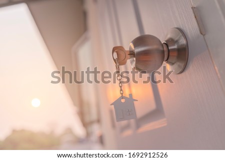 House key on house shaped keyring in the lock of door,Sunset background Foto stock © 