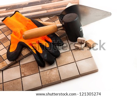 Ceramic tile, trowel, a rubber mallet and rubber glove on a white background