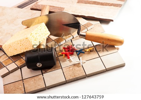 Different types of ceramic tiles, trowel, a rubber mallet, the crosses on a white background