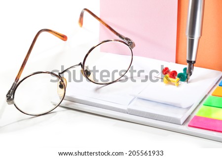 Pen tip, glasses, pieces of paper, paper for notes on a white background