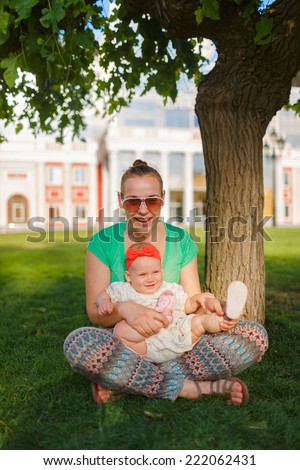 Mom doing yoga with your child. Baby crawling on the grass on a background of sitting his mom. The kid runs away from his mother.