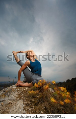 Woman doing yoga against the setting sun. Fitness classes outdoors. Stormy sky with sunshine. Attractive fitness woman, lifestyle portrait, caucasian model