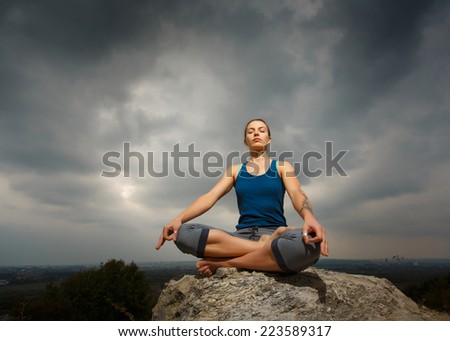 Woman doing yoga against the setting sun. Fitness classes outdoors. Stormy sky with sunshine. Attractive fitness woman, trained female body, lifestyle portrait, caucasian model