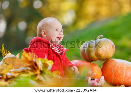 Child with his eyes closed. Happy little child, baby girl laughing and playing in the autumn on the nature walk outdoors.  Cute baby girl with pumpkins in autumn garden.