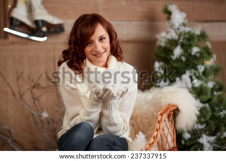 Beautiful brunette in white sweater and jeans holding snow. Christmas mood