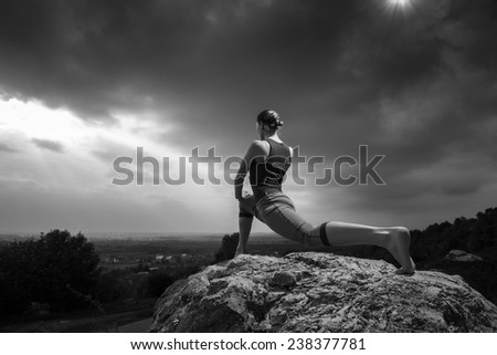 Woman practicing yoga pose outdoors over sunset sky background. Fitness classes outdoors