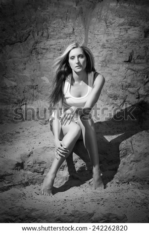 Black and white photo of a beautiful blonde, sexy appearance that posing in denim shorts and white T-shirt in the Canyon sandy