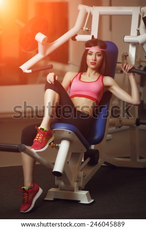 Sexy brunette with long hair and sporting appearance posing in the gym.