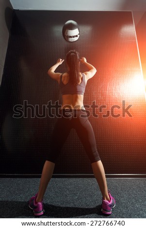 Attractive, muscular young woman throws up a medicine balls