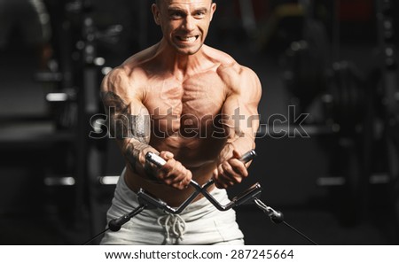 Close-up of a male bodybuilder working out at gym. Bodybuilding, posing, black background, muscles - the concept of bodybuilding. Article about bodybuilding.