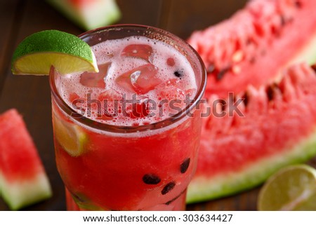 Glass of watermelon juice with slice of lime and ice cubes