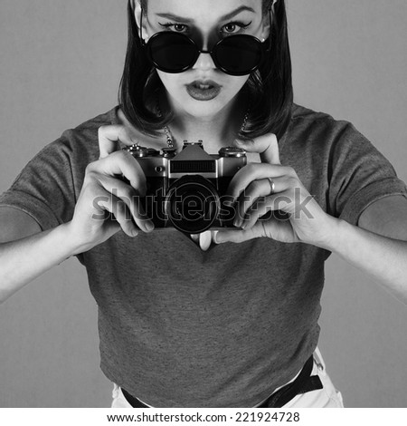 Young attractive fashionable woman with old-school camera wearing glasses