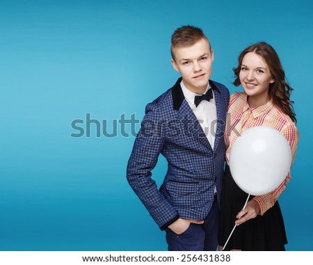Happy smiling couple boy and beautiful holding white balloon on blue background. Hipster style.