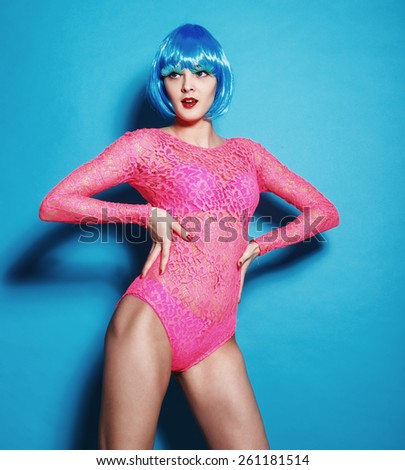 Fashion beautiful woman in pink bodysuit with blue hair and trendy hairstyle on a blue background. Perfect body. Disco punk fashion style club Party Girl