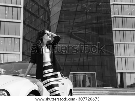 Beautiful business woman on the background of the modern office near the sport car