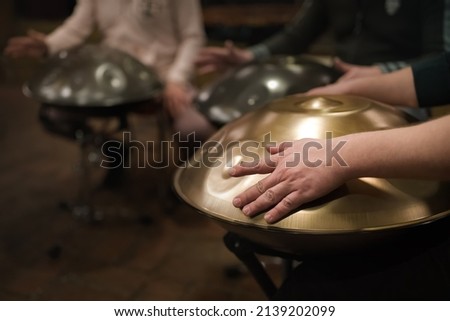 A musician's hand playing the handpan with other people. Handpan is a term for a group of musical instruments that are classified as a subset of the steelpan.  Stock fotó © 