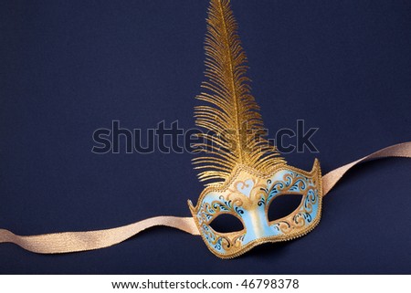 blue and gold feathered mask on a dark background