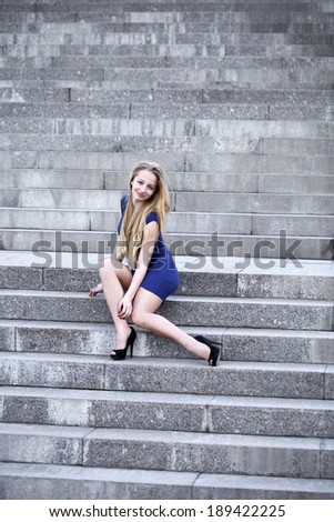 Young woman in blue dress sitting on the stone steps