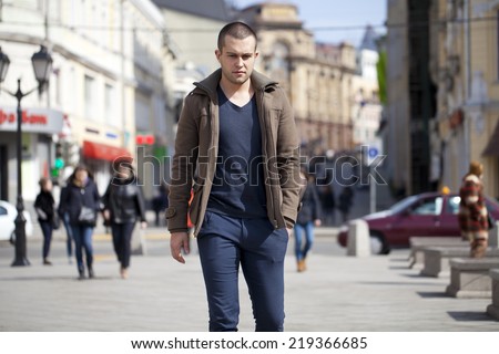 Young male fashion model walking in street