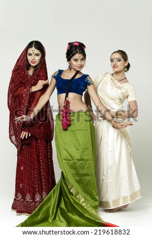 Three beautiful young women in indian dress on gray background
