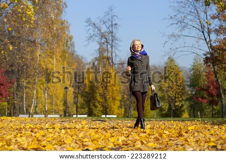Full length, walking happy woman in autumn park