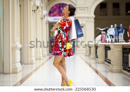 Beautiful young woman in color flowers dress walking in the shop